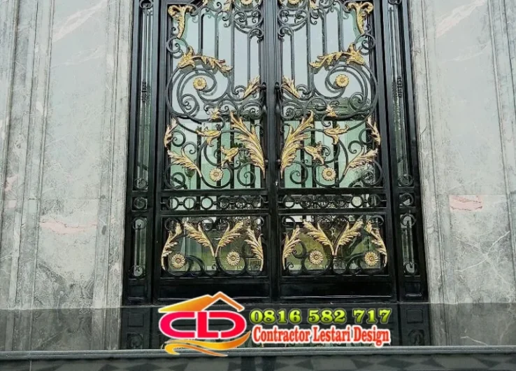 Pintu besi klasik warna hitam dengan ornamen daun dan bunga emas pada dinding marmer abu-abu