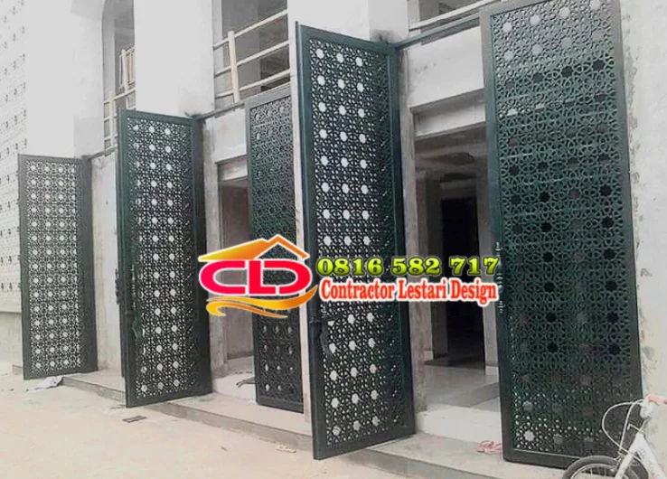 Pintu pagar besi minimalis warna hijau tua dengan pola geometris berlubang pada fasad bangunan