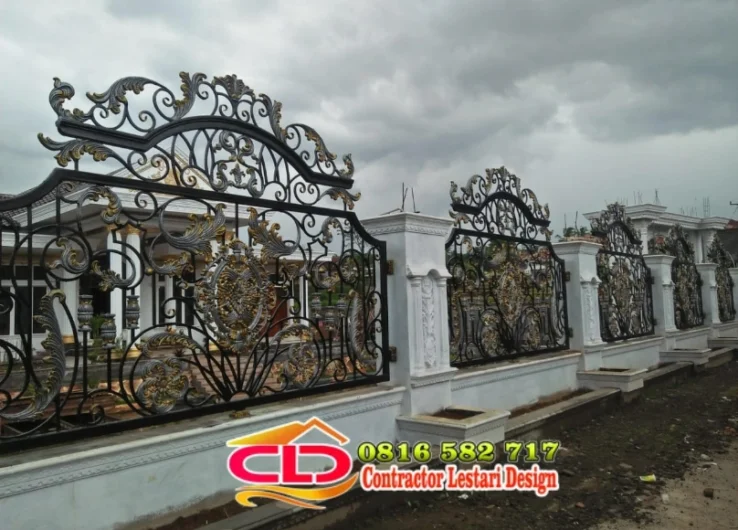 Pagar besi klasik modern warna hitam dengan aksen emas dan mahkota sulur di antara pilar putih