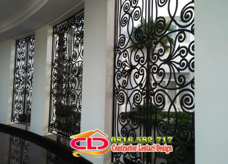 Panel pagar besi tempa mewah warna hitam dengan motif sulur spiral di antara pilar putih